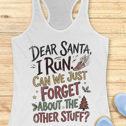 White racerback tank top displayed on a light wooden surface, featuring a festive running-themed typography design. The graphic includes the humorous text: “DEAR SANTA, I RUN. CAN WE JUST FORGET ABOUT THE OTHER STUFF?” Decorative holiday accents surround the text, including a winged running shoe, holly sprigs with red berries, gold stars, snowflakes, and a Christmas tree. The design uses black, red, green, and gold lettering for a playful holiday look. Partial blue athletic shoes are visible in the lower co