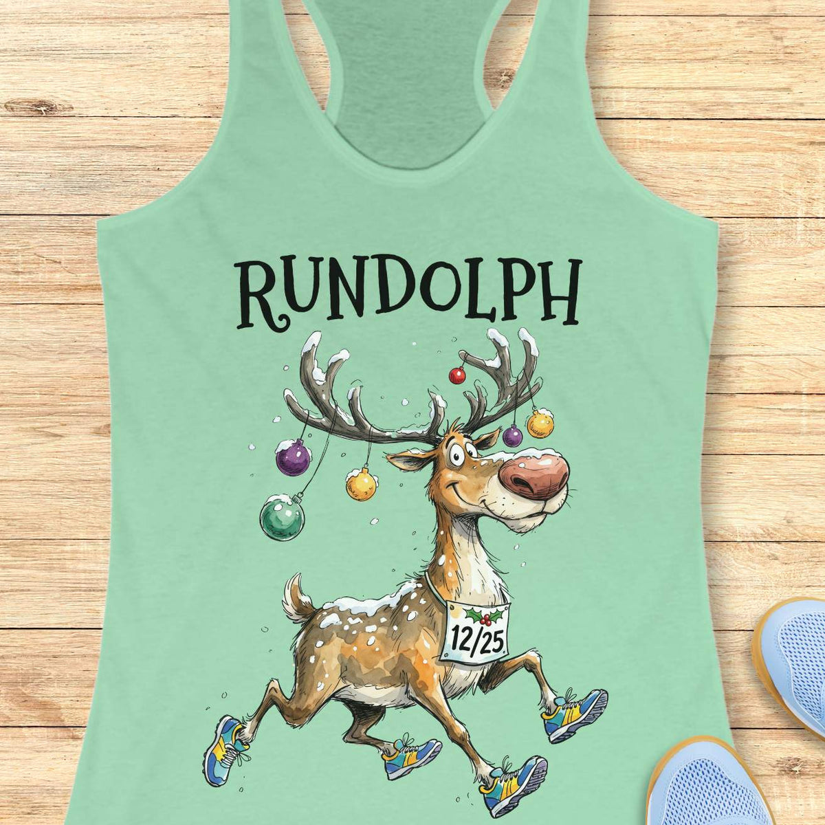 mint racerback tank top featuring the word “RUNDOLPH” above a playful cartoon reindeer running in colorful athletic shoes. The reindeer has snow-dusted antlers decorated with hanging Christmas ornaments and wears a race bib displaying “12/25.” Snowflakes are scattered throughout the design, adding a festive winter feel. The humorous artwork combines holiday cheer and running culture, making it perfect for runners who love Christmas-themed race apparel.