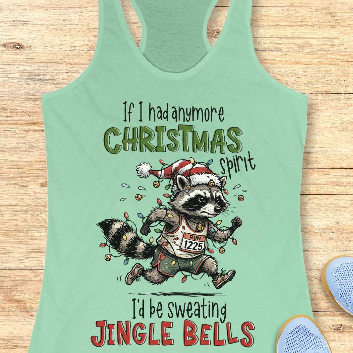 mint racerback tank top featuring the humorous Christmas running quote “If I had anymore Christmas spirit I’d be sweating Jingle Bells.” The design shows a cartoon raccoon runner wearing a Santa hat and wrapped in colorful Christmas lights while running in athletic gear. The raccoon wears a race bib labeled “RUN 1225” and is surrounded by festive holiday lights and jingle bells. The playful artwork combines Christmas cheer, running humor, and woodland charm, making it perfect for runners who love holiday r