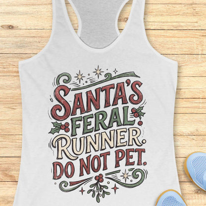 white racerback tank top featuring the festive phrase “Santa’s Feral Runner, Do Not Pet” in large vintage-style lettering. The design includes red, white, and green text accented with holly leaves, red berries, stars, swirls, and mistletoe-inspired elements, creating a playful Christmas theme for runners. The tank top is displayed on a light wood background with partial blue running shoes visible in the corners.