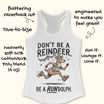 white racerback tank top featuring the humorous Christmas running phrase “DON’T BE A REINDEER. BE A RUNDOLPH.” in bold black lettering. The design includes a cartoon reindeer wearing running shoes and a race singlet with the words “SLEIGH IT,” sprinting beneath festive garland, ornaments, and stars. The playful holiday-themed artwork combines Christmas cheer with a runner's sense of humor. The tank top is displayed on a light wood background with partial blue running shoes visible in the corners.