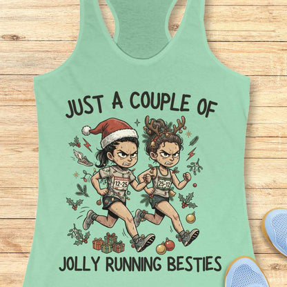 A mint green racerback tank top featuring a cartoon graphic of two Christmas-themed marathon runners with the text 'JUST A COUPLE OF JOLLY RUNNING BESTIES'. The tank top is displayed flat on a light wood background with a blue shoe partially visible in the corner.