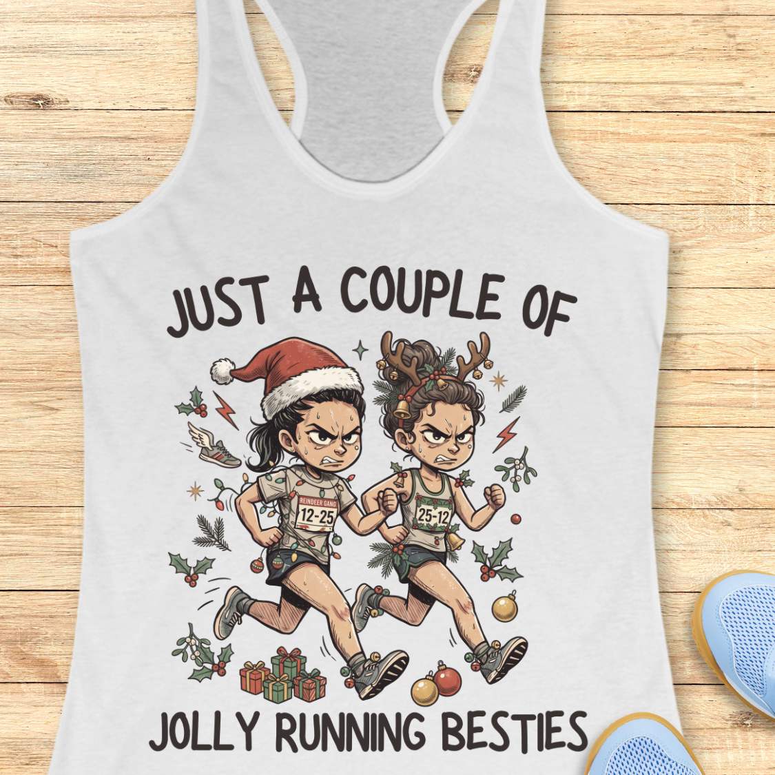 White racerback running tank top displayed on a wooden background featuring a festive illustration of two runners in holiday outfits. One runner wears a Santa hat and the other wears reindeer antlers adorned with Christmas decorations. The runners are dressed in race gear, surrounded by holly, ornaments, presents, and holiday accents. The design includes the text: “JUST A COUPLE OF JOLLY RUNNING BESTIES.” Blue running shoes are partially visible at the bottom corners of the image.