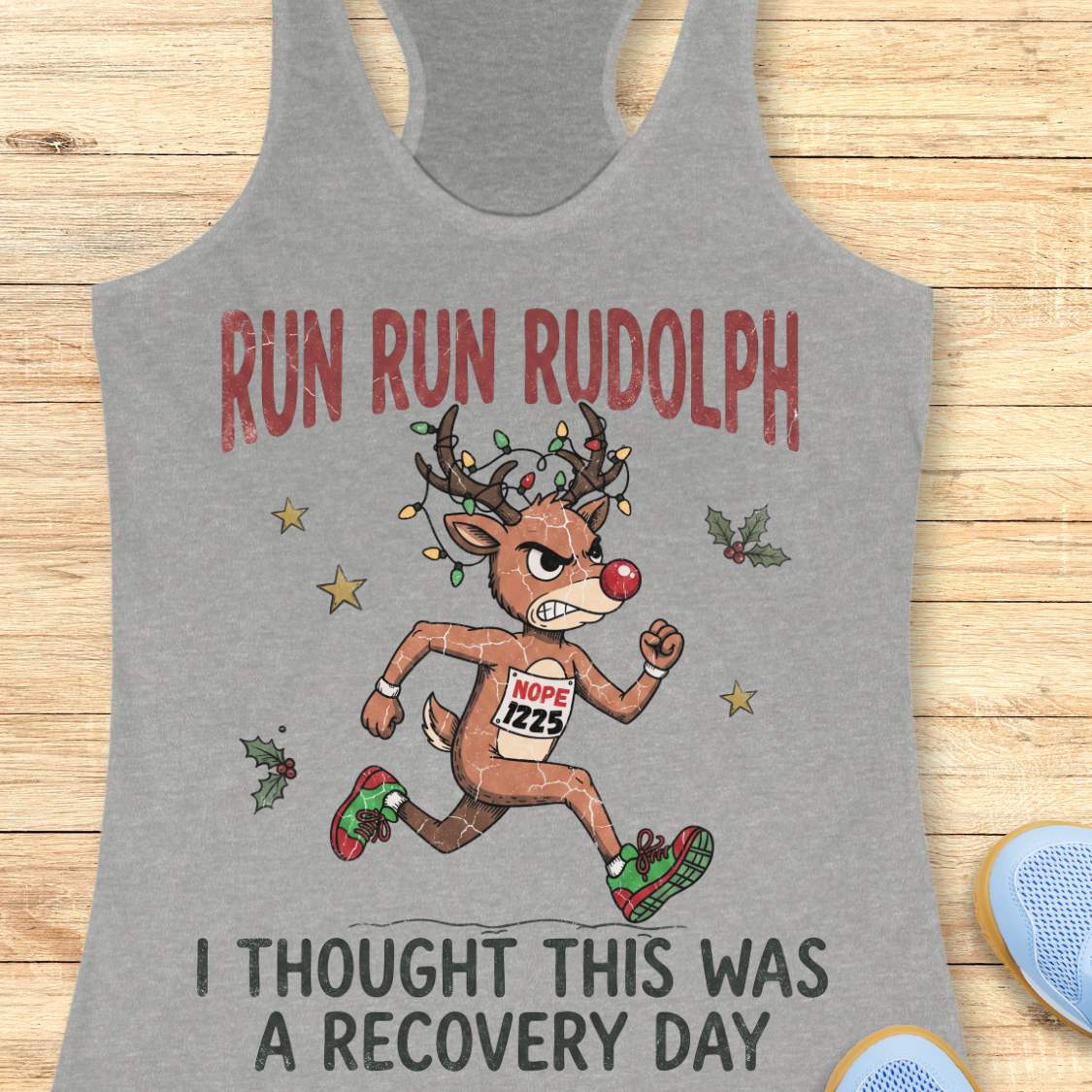Funny Christmas runner tank top featuring Rudolph the Red-Nosed Reindeer dressed as a runner, sprinting in red and green running shoes with a race bib that reads "NOPE 1225." Rudolph's antlers are wrapped in colorful Christmas lights, and festive holly leaves and stars surround the character. Large distressed text reads, "RUN RUN RUDOLPH" above the illustration and "I THOUGHT THIS WAS A RECOVERY DAY" below. The design is printed on a mint green racerback tank top and combines holiday humor with a relatable 