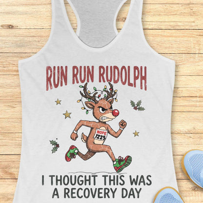 Funny Christmas runner tank top featuring Rudolph the Red-Nosed Reindeer dressed as a runner, sprinting in red and green running shoes with a race bib that reads "NOPE 1225." Rudolph's antlers are wrapped in colorful Christmas lights, and festive holly leaves and stars surround the character. Large distressed text reads, "RUN RUN RUDOLPH" above the illustration and "I THOUGHT THIS WAS A RECOVERY DAY" below. The design is printed on a mint green racerback tank top and combines holiday humor with a relatable 