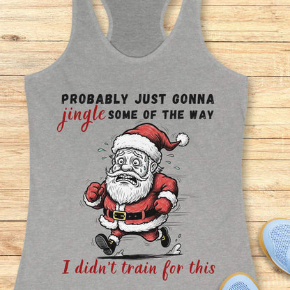 A grey racerback tank top laid flat on a light wood background, featuring a humorous graphic of a running Santa Claus with the text 'PROBABLY JUST GONNA jingle SOME OF THE WAY I didn't train for this'.
