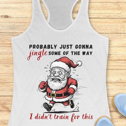 A white racerback tank top laid flat on a light wood background, featuring a humorous graphic of a running Santa Claus with the text 'PROBABLY JUST GONNA jingle SOME OF THE WAY I didn't train for this'.