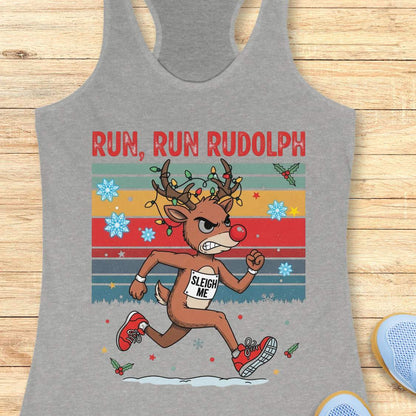 A grey racerback tank top with a colorful 'RUN, RUN RUDOLPH' holiday graphic on the front, shown on a light beige background with decorative text callouts around it.