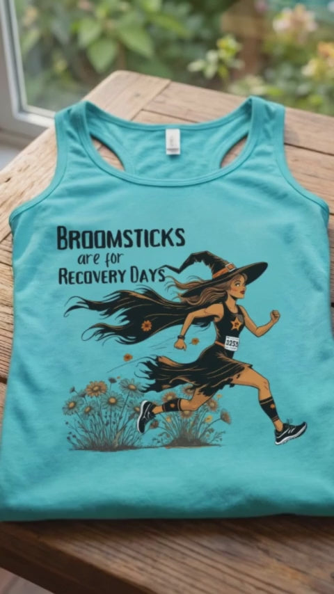 video of a Halloween themed women  runner mblue tank top, folded on a coffee table, with a smart watch and a hot chocolate mug, with the slogan - Broomsticks are for recovery day, with a running witch. 