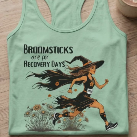 video of a Halloween themed women  runner mint tank top, folded on a coffee table, with a smart watch and a hot chocolate mug, with the slogan - Broomsticks are for recovery day, with a running witch. 