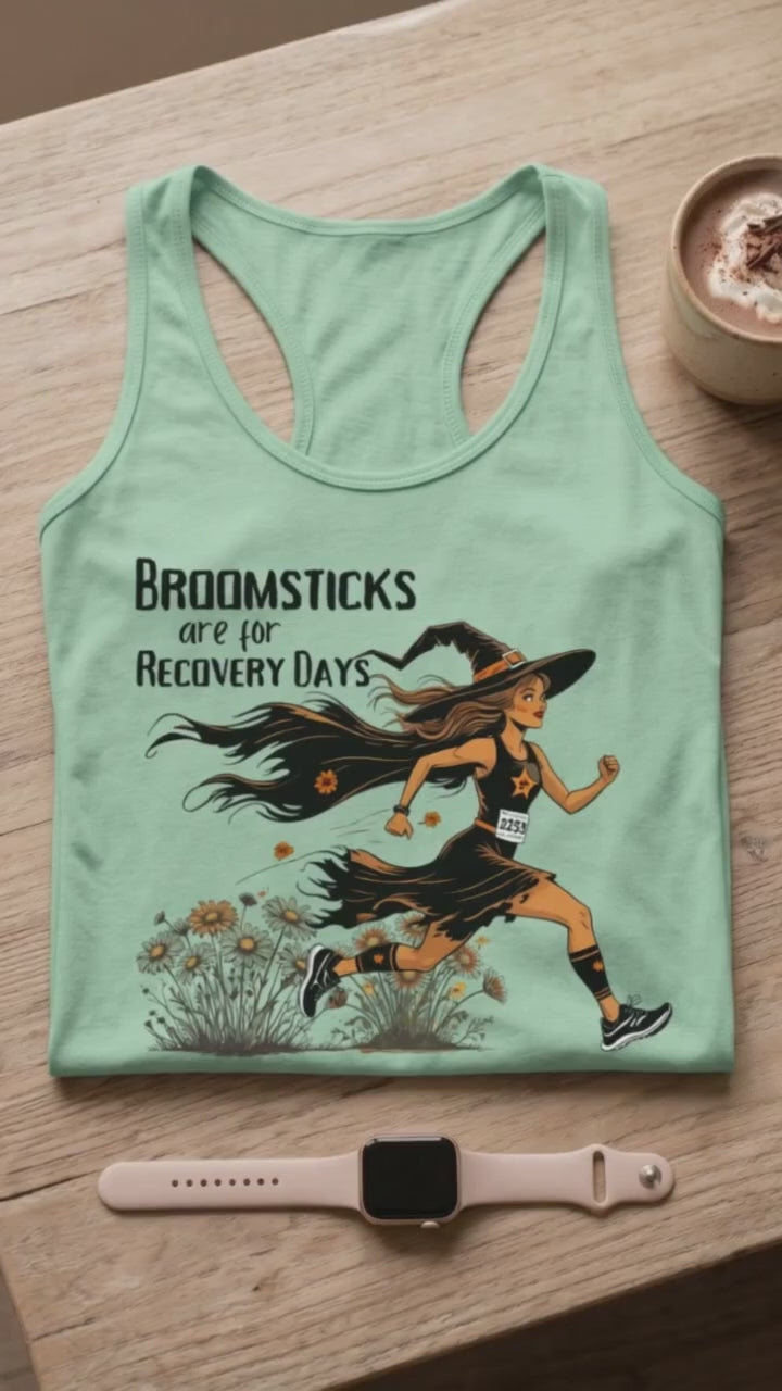 video of a Halloween themed women  runner mint tank top, folded on a coffee table, with a smart watch and a hot chocolate mug, with the slogan - Broomsticks are for recovery day, with a running witch. 
